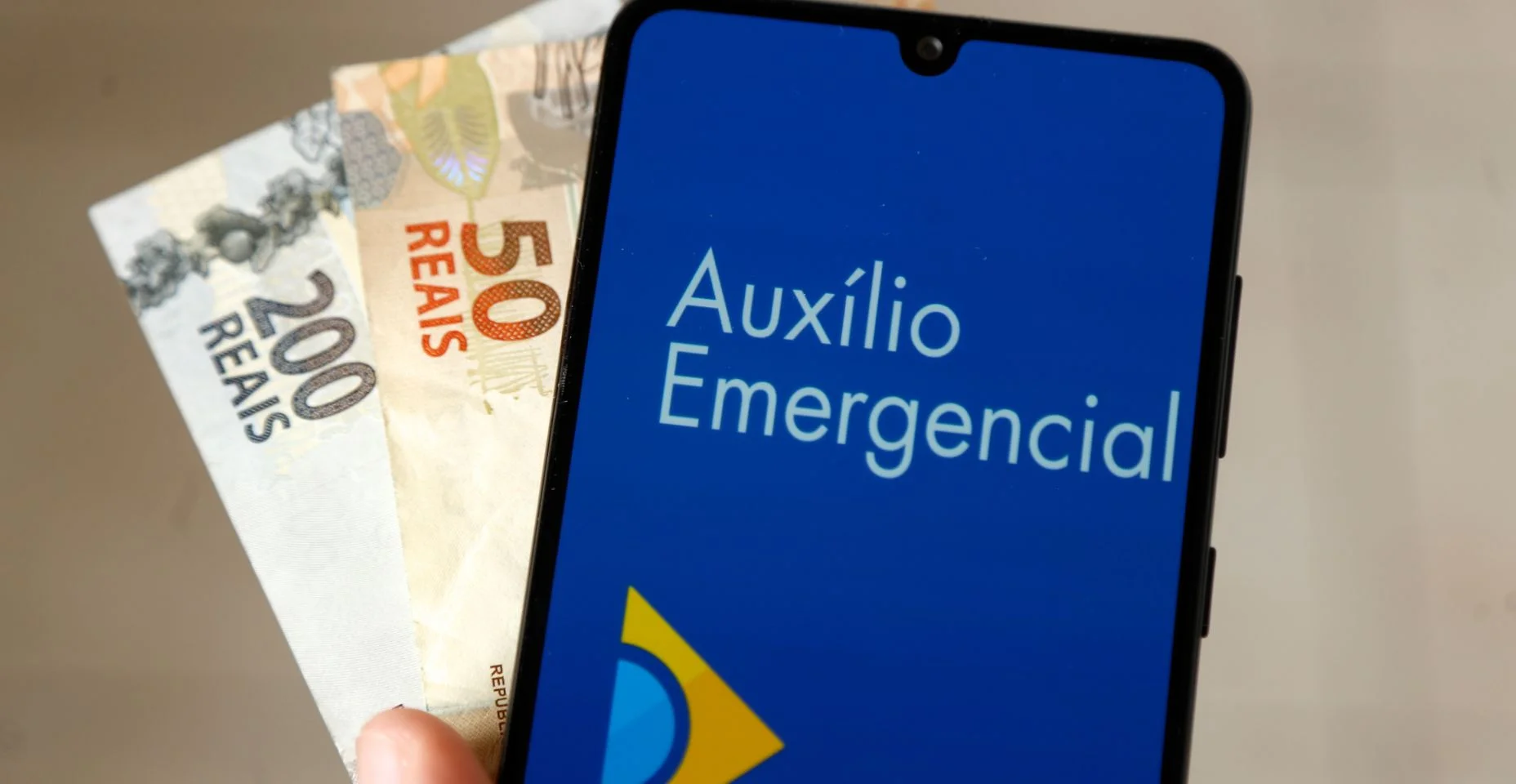 dinheiro e celular com aplicativo Auxilioemergência