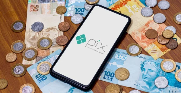 Logotipo do Pix na tela do smartphone com várias moedas ao redor. O Pix é o novo sistema de pagamento e transferência do governo brasileiro e brasileiro