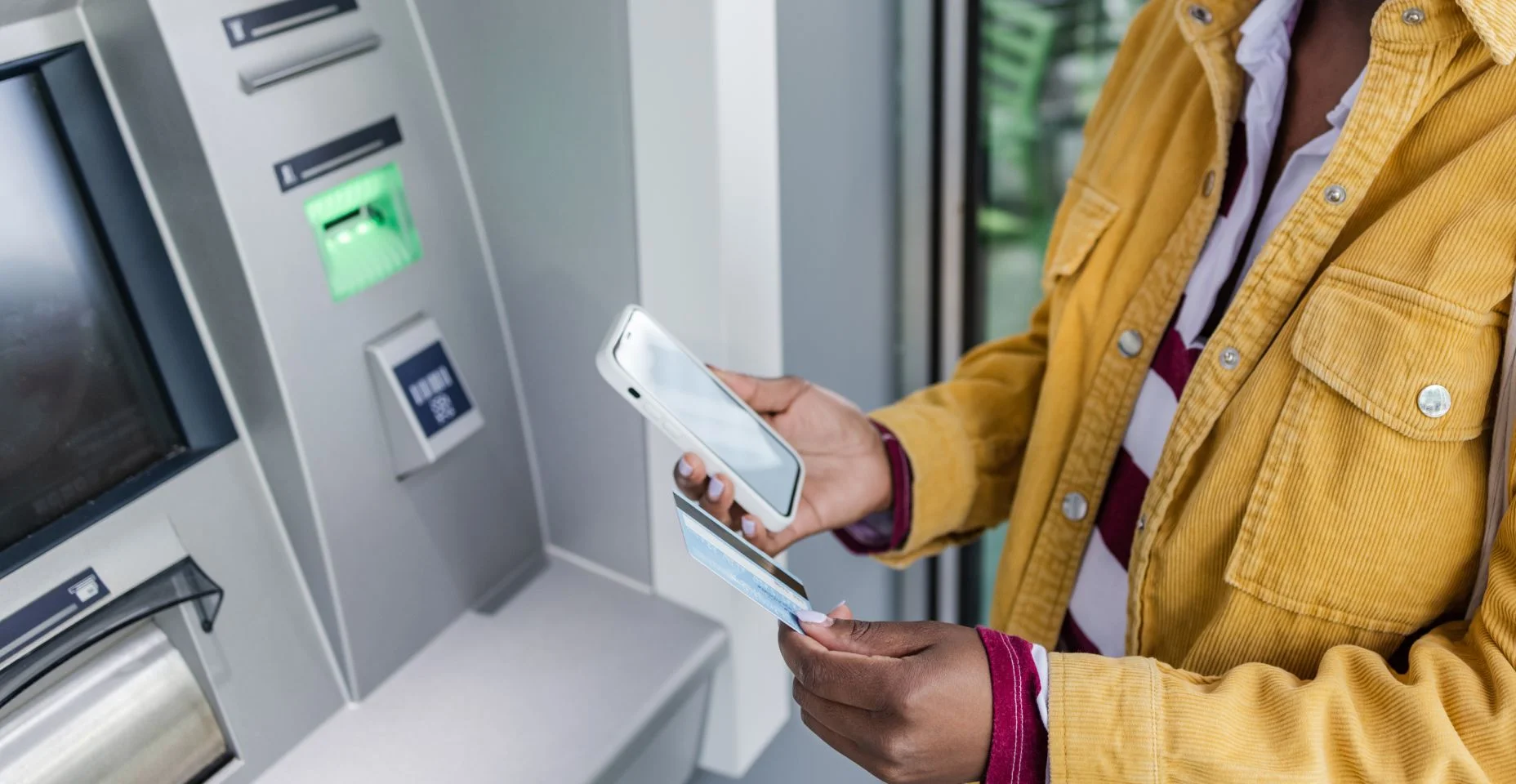 Mulher afro-americana está retirando dinheiro no caixa eletrônico ao ar livre