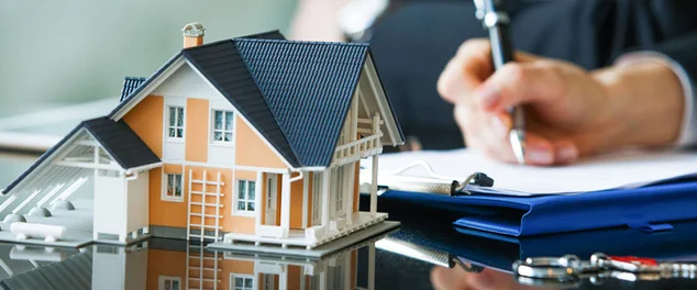 Homem com uma mini casa e um contrato ao lado para ilustrar o artigo sobre financiamento imobiliário em bancos