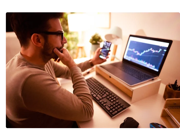 Homem olhando para o computador e vendo crescimento de investimentos