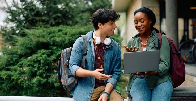 Estudantes universitários felizes e-learning enquanto usam laptop no campus.