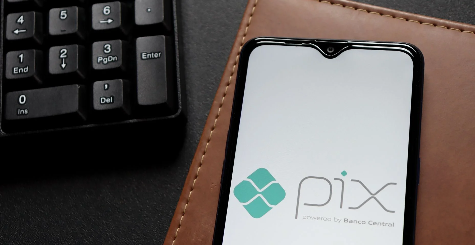 Logotipo Pix na tela do smartphone na mesa de escritório. Pix é o novo sistema de pagamentos instantâneos do Banco Central do Brasil.
