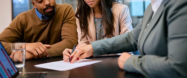 Jovem casal assinando contrato com corretor de seguros no escritório