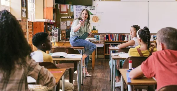 Professor divertido, feliz e animado conversando com os alunos na sala de aula da escola com o grupo de crianças que aprendem. Mulher confiante, amigável e legal fazendo diversas perguntas sobre educação infantil na aula de estudo