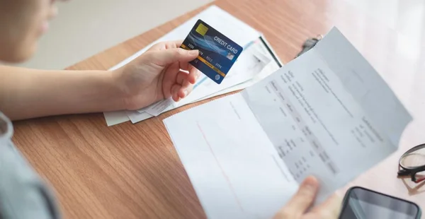 A opinião superior das mulheres prende mão o cartão de crédito e que verific, verific, valida, transação do dinheiro da análise com factura, contas e no frame inclui o smartphone e os vidros