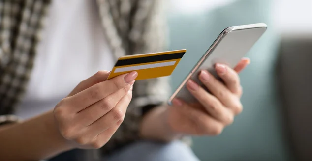 Foto de senhora segurando celular e cartão de crédito