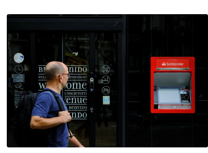 homem passando por um caixa eletronico do banco santander