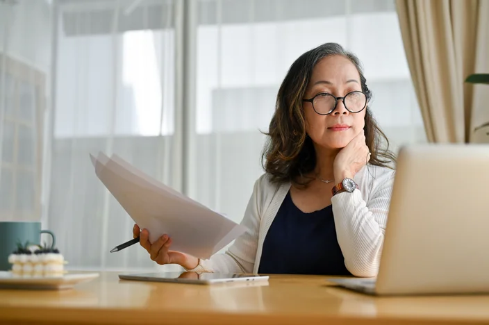 Mulher de negócios asiática de meia idade concentrada usando computador portátil