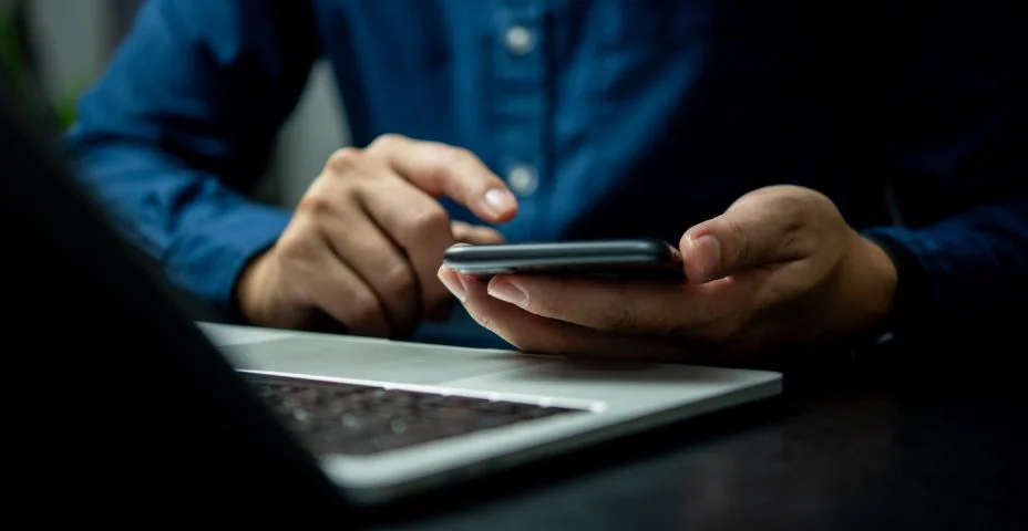 Um homem está usando um celular enquanto está sentado em uma mesa