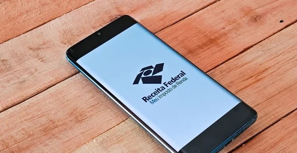 Smartphone com o logotipo da Receita Federal - Meu Imposto de Renda na tela. Declaração de Imposto de Renda no Brasil.
