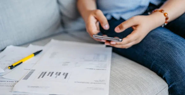 Mulher nova verificando suas finanças usando o telefone inteligente