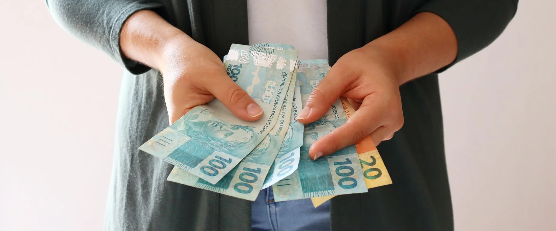 Jovem contando dinheiro. Dinheiro brasileiro. Conceito de economia brasileira.