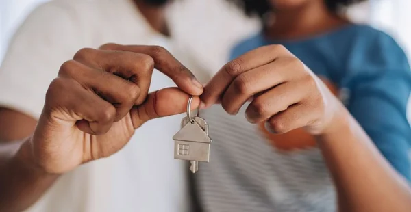 Duas mãos segurando um molho de chaves com um chaveiro de casa
