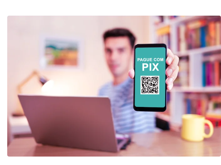 Homem segurando celular e mostrando uma tela com o nome pix e um QRcode