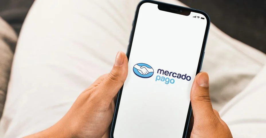 Female hand holding a smartphone with Mercado Pago app on the screen.