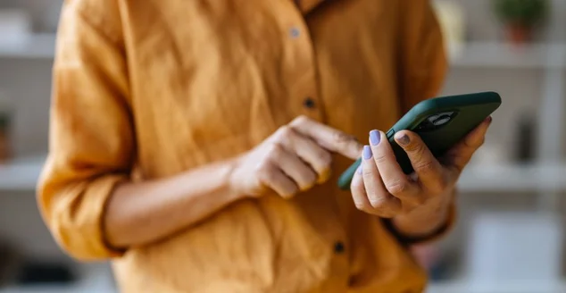 Uma empresária irreconhecível usando seu celular enquanto trabalha no escritório