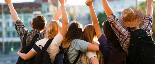 Turistas dos amigos com as mãos de aumentação das mochilas