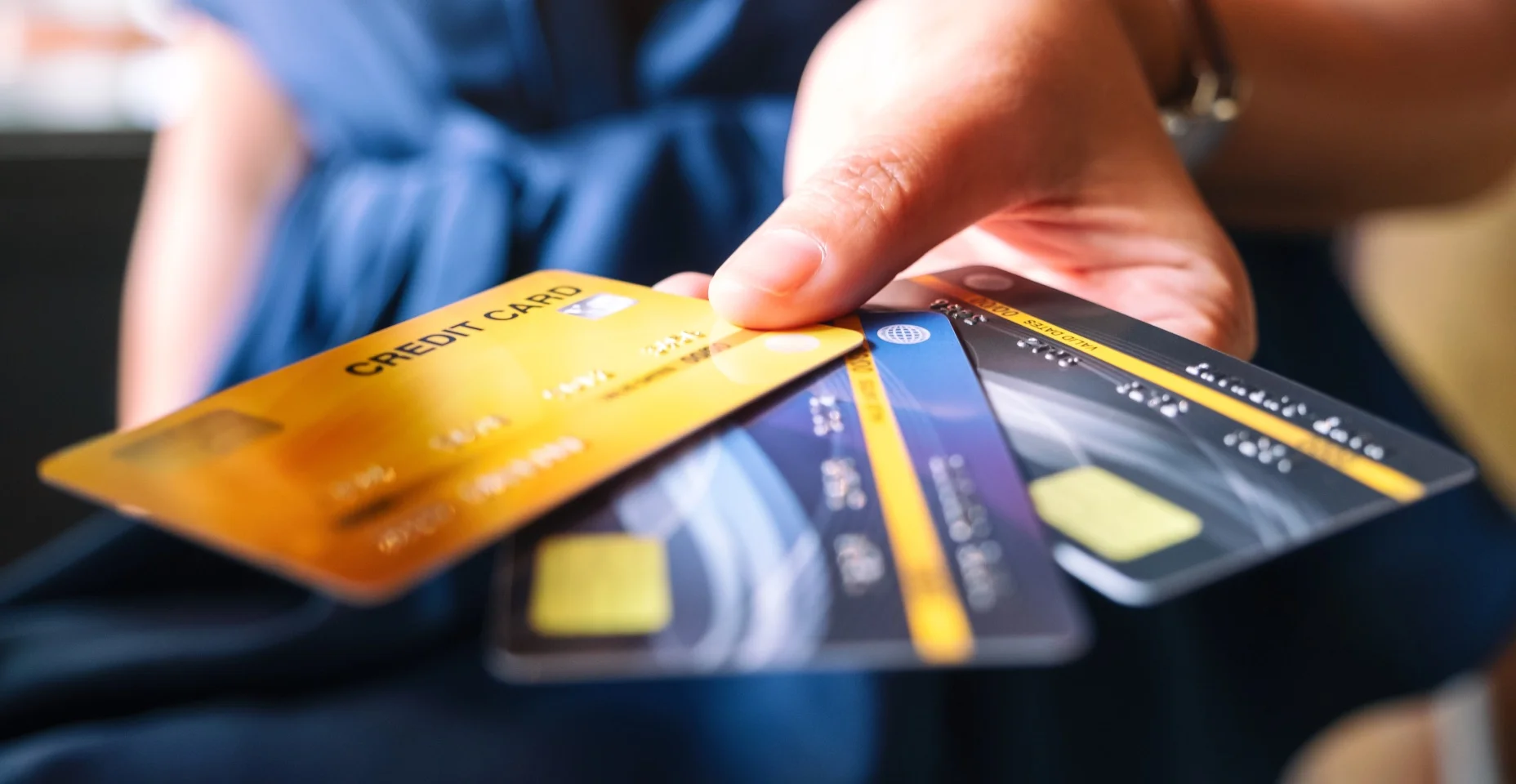 Imagem aproximada de uma mulher segurando e mostrando cartão de crédito