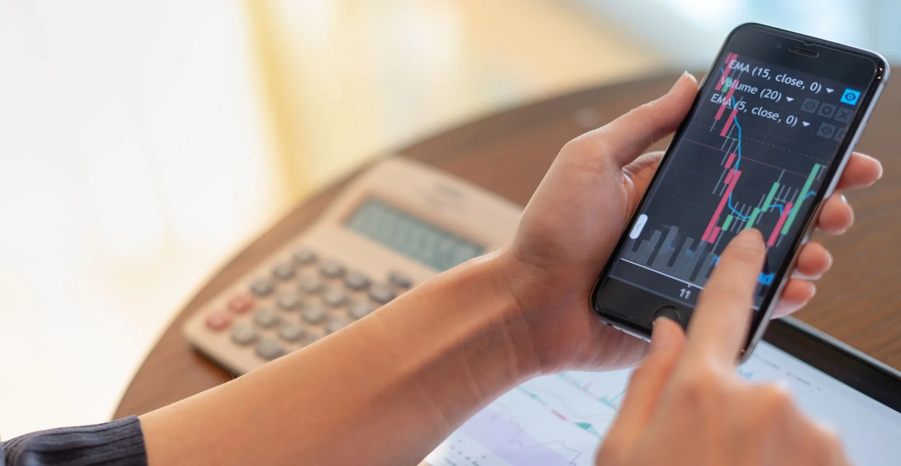 Close-up mão segurando o celular com gráfico de análise e o gráfico de tendências com aplicativo de mercado conjunto de ações que em todos os lugares pode estar sendo negociado.