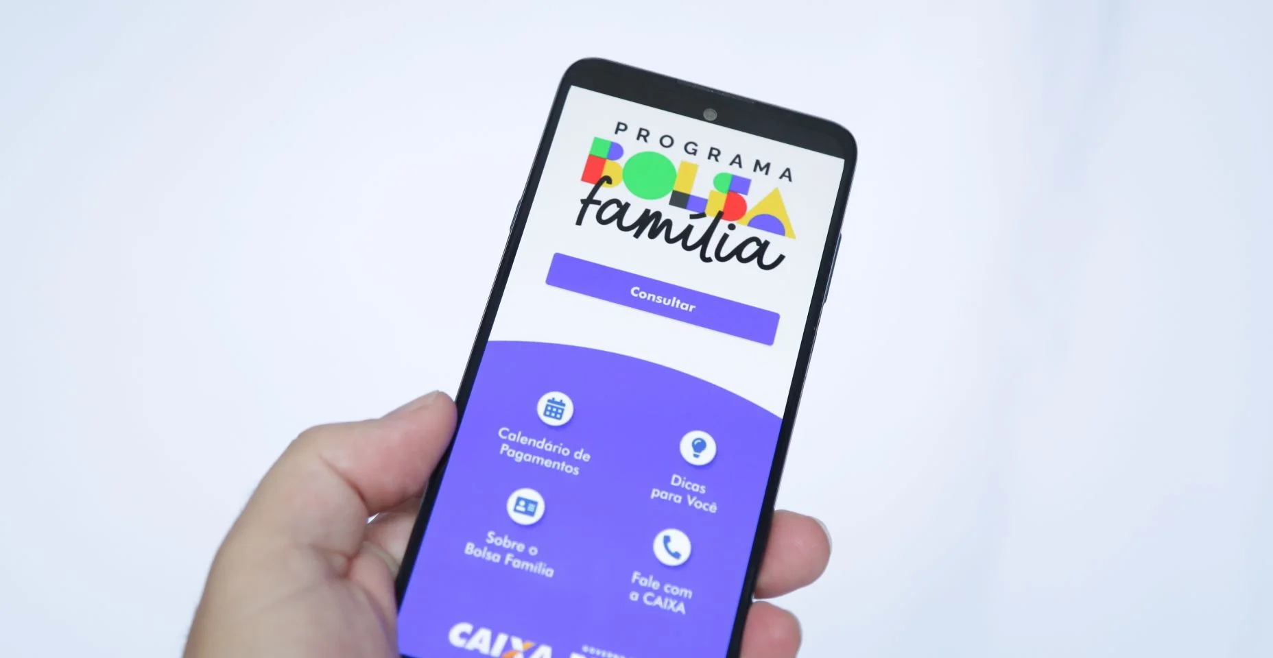 Mão masculina segurando um smartphone com o aplicativo Bolsa Familia do governo.