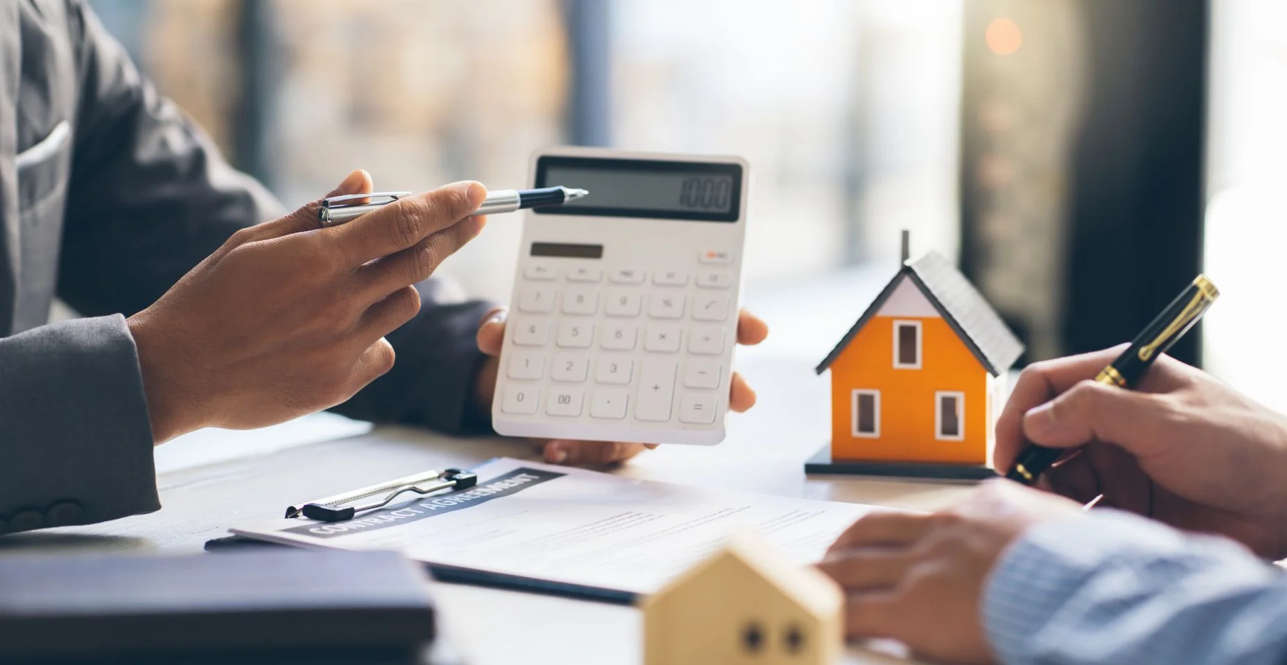 Modelo da casa com o agente e o cliente que discutem para que o contrato compre, começ bens imobiliários ou propriedade do empréstimo do empréstimo.