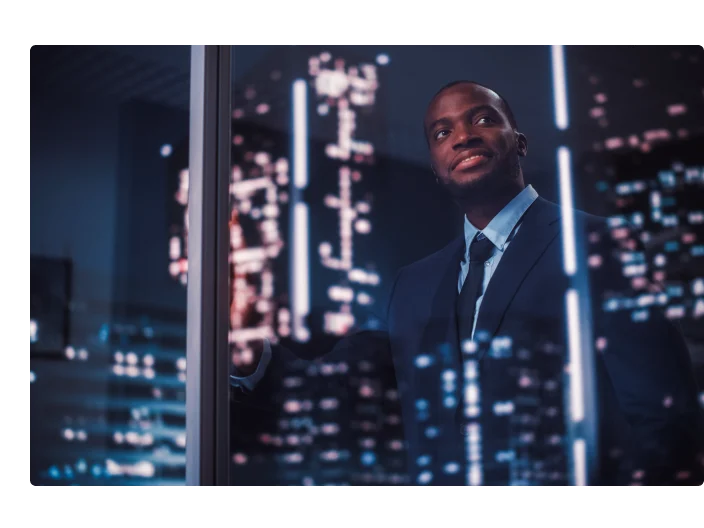 Empresário negro de sucesso em um terno sob medida em seu escritório olhando para fora da janela em Night City. Gerente de investimento bem-sucedido trabalhando no planejamento tardio da estratégia de compra de serviços de comércio eletrônico