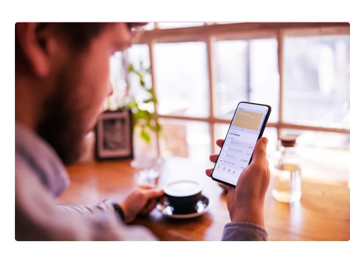 Homem tomando café e olhando para o celular