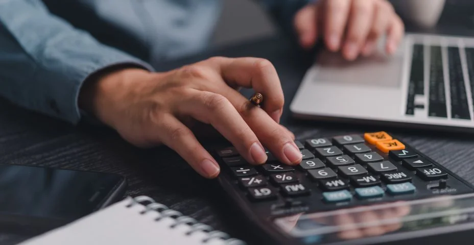 Empresário utilizando calculadora escrituração de folha de pagamento e orçamento fiscal. Documento de negócios: finanças, contabilidade, investimento