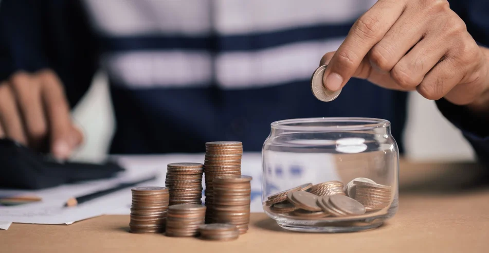 Empresário segurando moedas colocando em vidro. conceito de economia de dinheiro para contabilidade financeira.