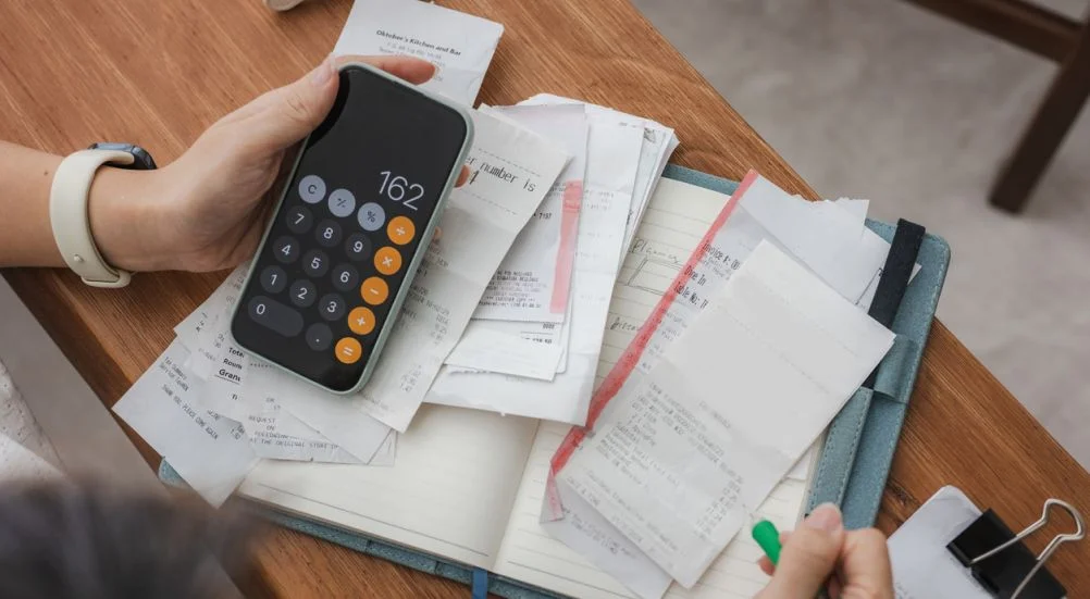 mulher gerenciando suas finanças domésticas com um smartphone, ela revisa contas financeiras. Os conceitos incluem planejamento financeiro, impostos, gastos, orçamento e desafios financeiros.