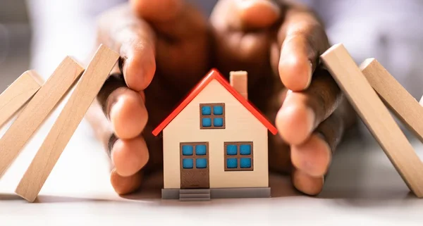 Mão protegendo uma casa