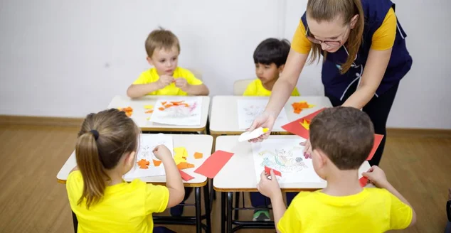 Visão de ângulo alto de crianças e professores fazendo atividade de arte