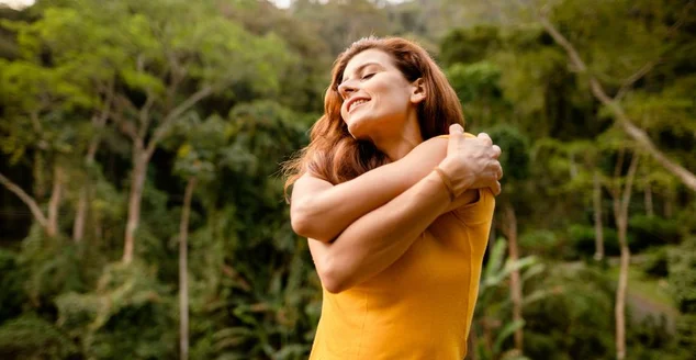 Mulher sorridente dando-se um abraço fora no verão