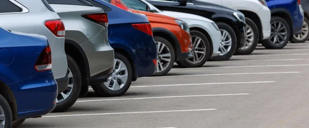 Linha de diferentes carros de cor no estacionamento asfáltico no dia nublado de verão