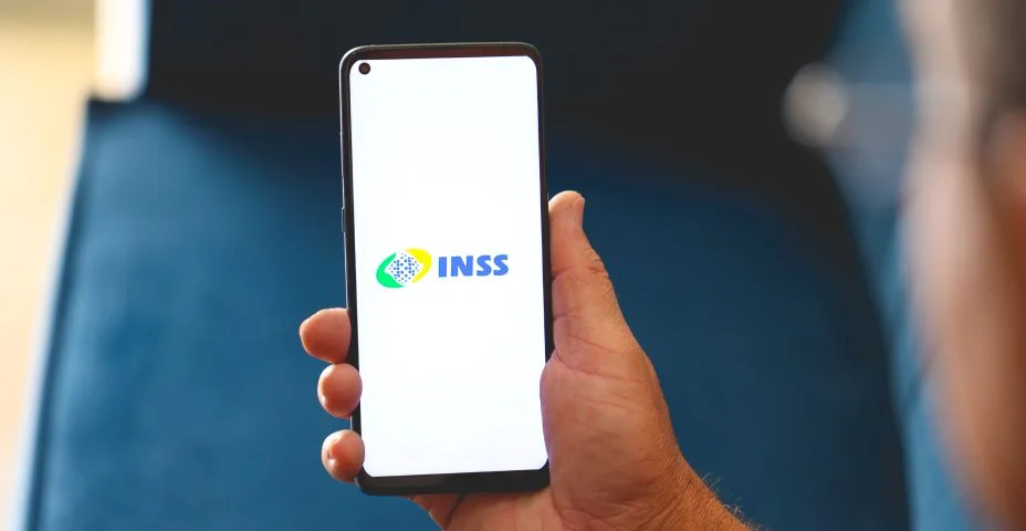 celular encostado no notebook com o logo do previdência social (inss) aberto