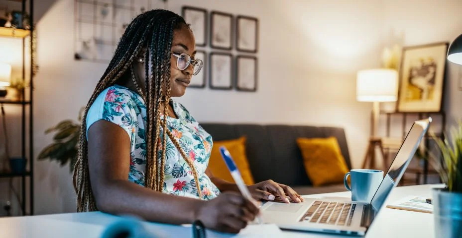 Estudante afro-americana estudando em casa e tomando notas de professor