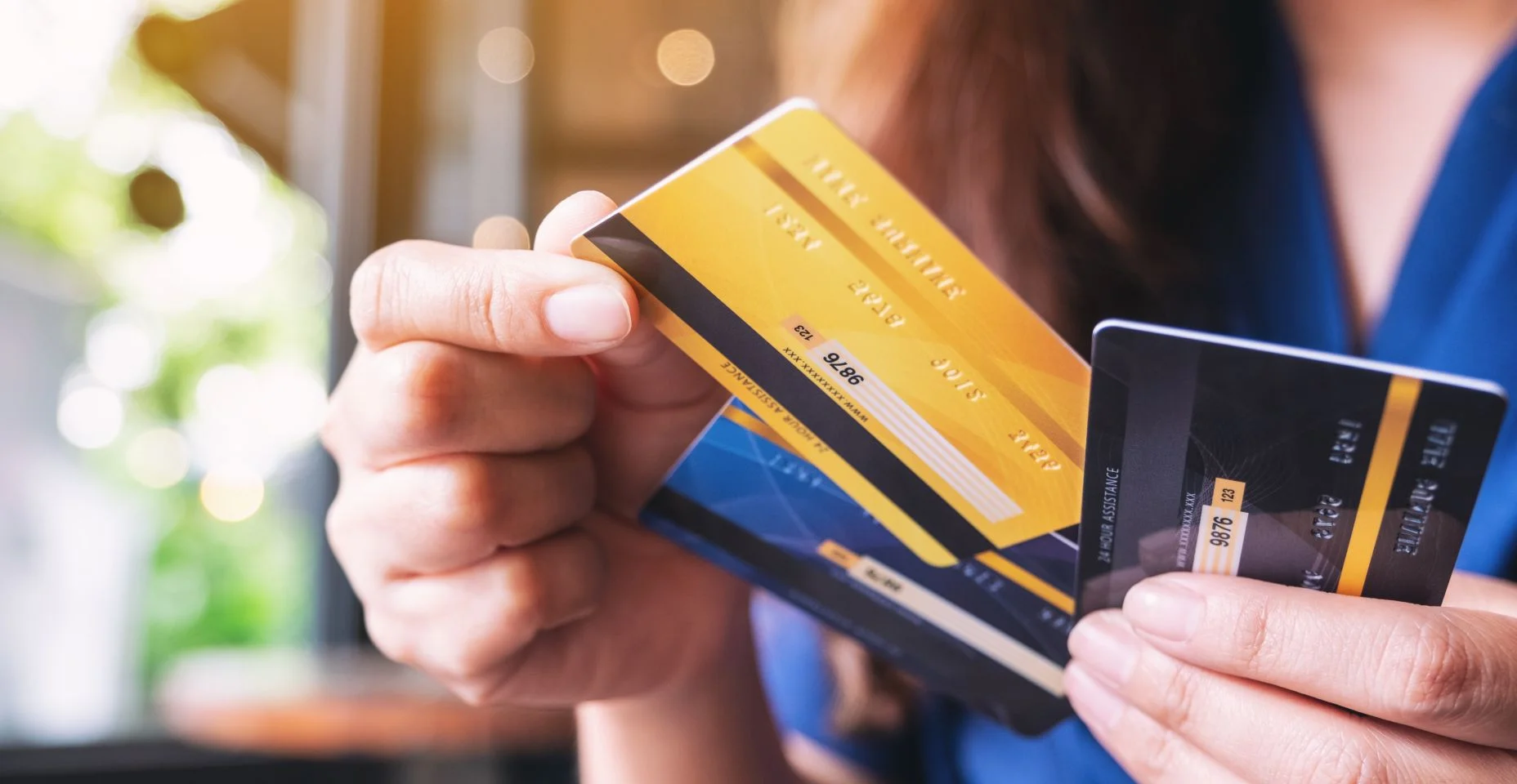 Imagem aproximada de uma mulher segurando e escolhendo um cartão de crédito para usar