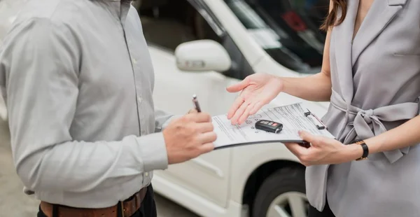 Negócio automotivo, venda de carros ou conceito de aluguel : Cliente feliz com agente de revendedor de carros fazendo acordo e assinando contrato de contrato de acordo em showroom de automóveis ou escritório de revendedor de carros.