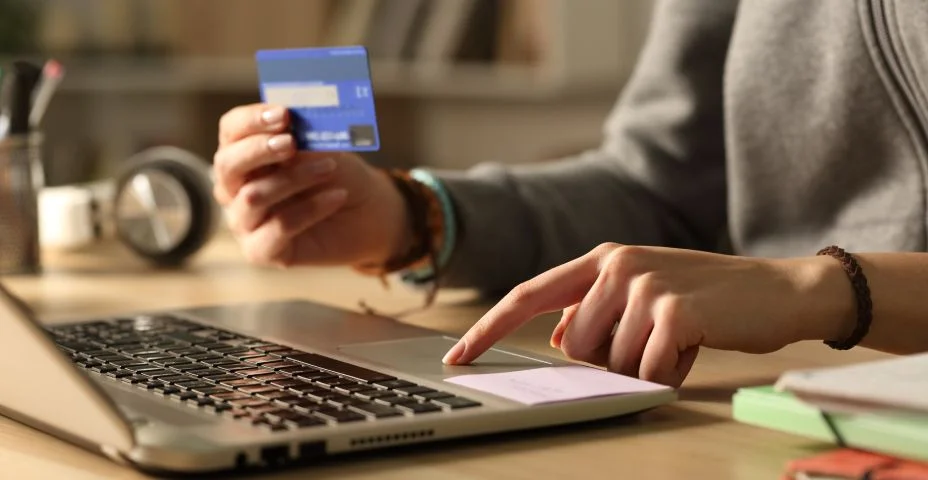 Mãos de estudante pagando com cartão de crédito no laptop à noite