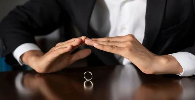 Homem de negócios que protege o anel de casamento com mãos na tabela