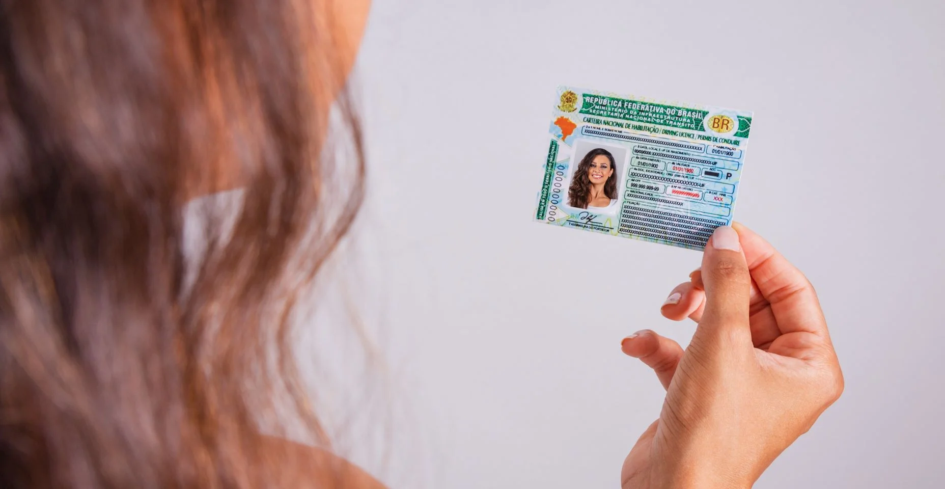 Mão segurando carteira de motorista, documento brasileiro.