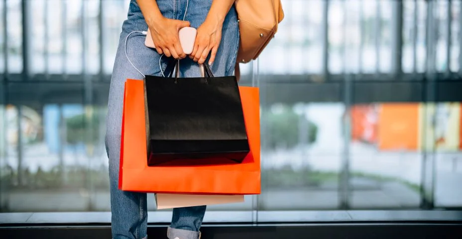 Uma mulher anônima segurando sacolas de compras em shopping center