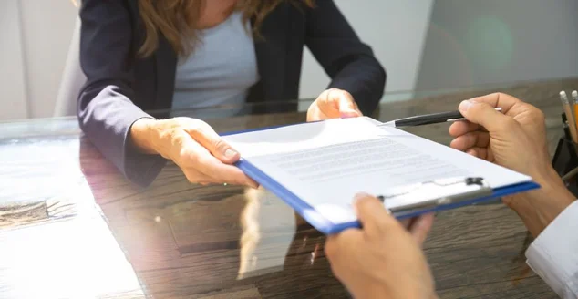 Close-up da mão de uma pessoa preenchendo um formulário de contrato