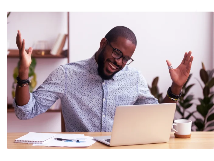 Homem feliz olhando para seu notebook e fazendo uma comemoração