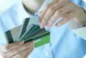 Mulher escolhendo entre vários cartões de crédito