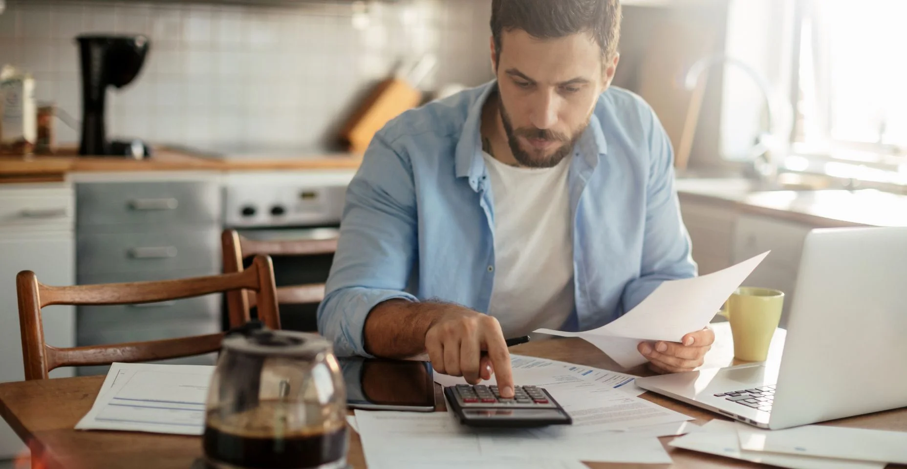 Jovem examinando suas finanças domésticas na cozinha