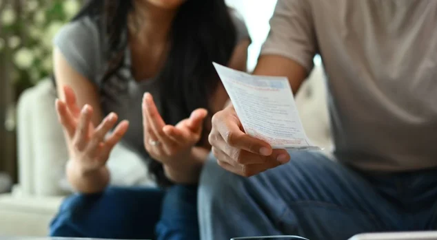 Casal com problemas financeiros, calculando o orçamento doméstico na sala de estar