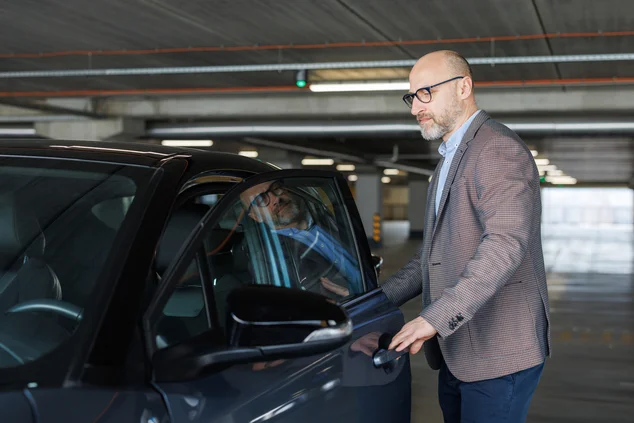 Foto de um empresário confiante entrando em seu carro em uma garagem