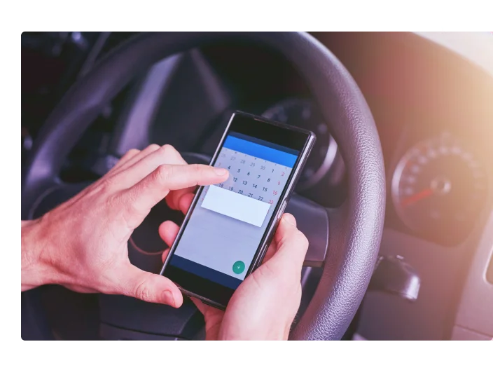Pessoa dentro de um carro com seu celular em mãos aberto no calendário